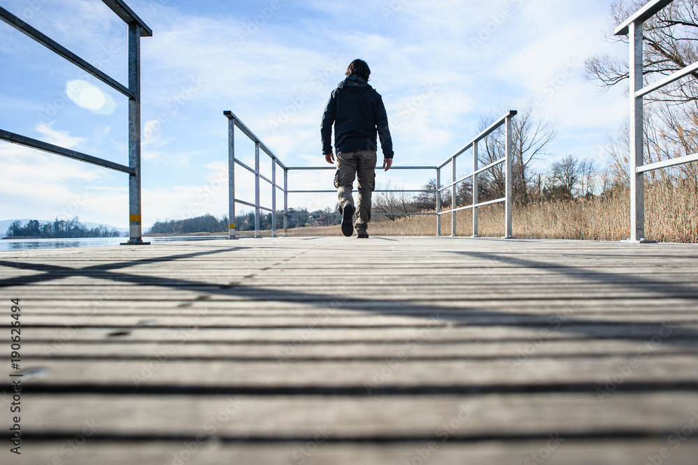 man walking on the pier on Lake Varese, Biandronno, Lombardy, Italy