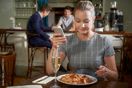 Female Food Blogger Posting Online Review Of Restaurant Meal Using Mobile Phone