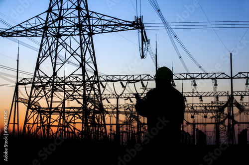 Electricity workers and pylon silhouette