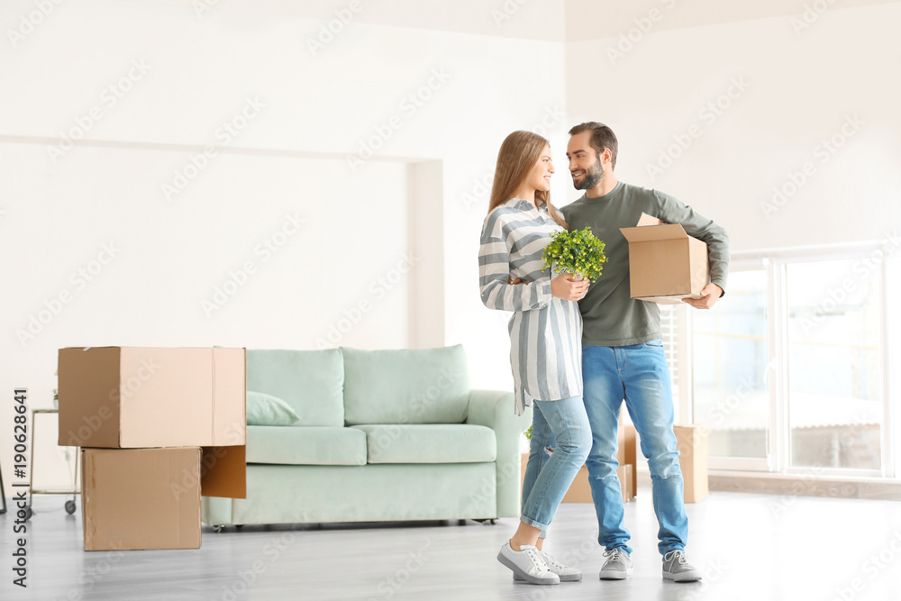 © Africa Studio - Young man holding moving box and woman with houseplant in room at new home © Africa Studio - Young man holding moving box and woman with houseplant in room at new home