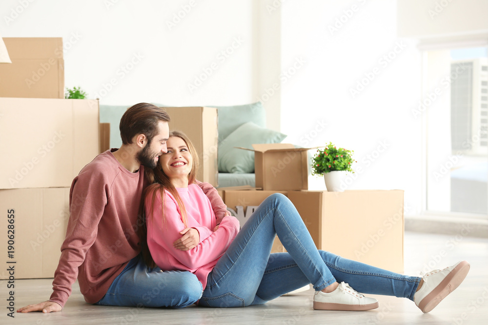 Young couple with moving boxes on floor in room Young couple with moving boxes on floor in room