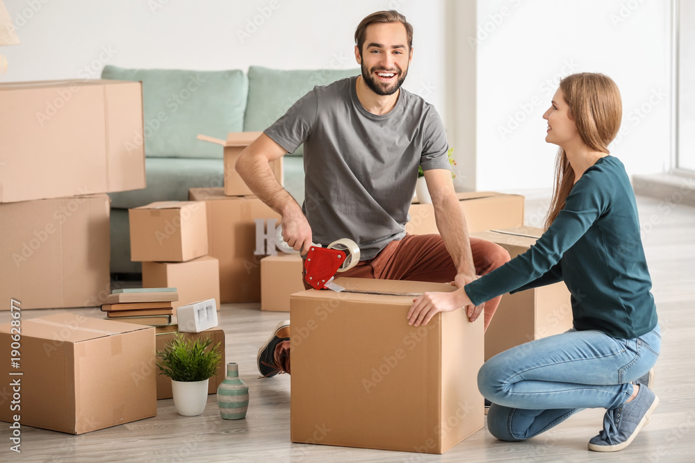 Young couple packing moving boxes, indoors Young couple packing moving boxes, indoors
