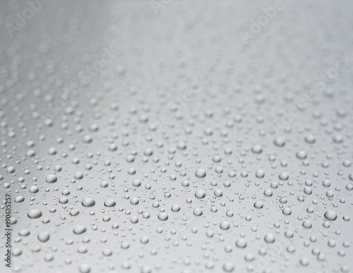 Clear water drops on light grey background. Shallow depth of field.