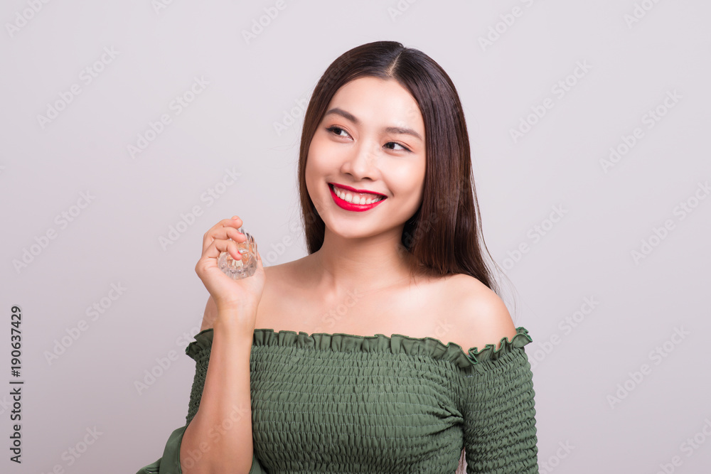 Young beautiful woman holding bottle of perfume and smelling aroma Young beautiful woman holding bottle of perfume and smelling aroma