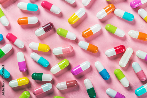 different color pills on a pink background. Drugs and medicines, concept