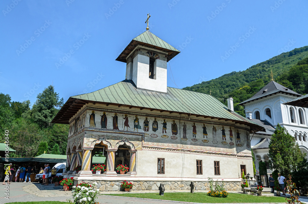 VALEA JIULUI, ROMANIA - AUGUST 1, 2017: Tourists visit the old Lainici Monastery on a summer's day, detail from the courtyard with exterior paintings.