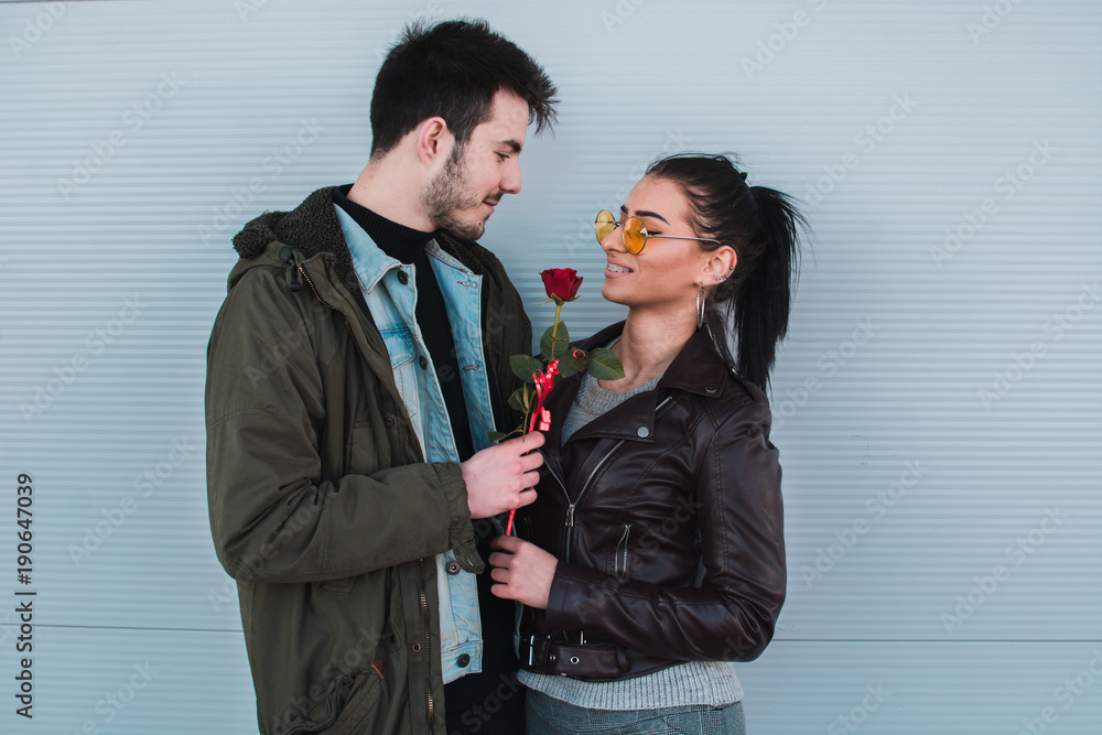 Attractive man gives rose, present to his girlfriend as a Valentines day present. Attractive man gives rose, present to his girlfriend as a Valentines day present.