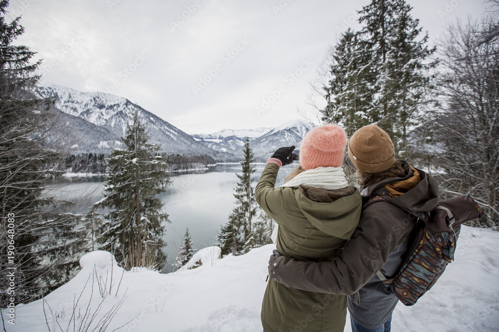 Couple taking a picture in alpine winter landscape with lake Couple taking a picture in alpine winter landscape with lake