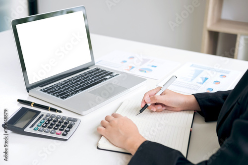 Female accountant calculations and analyzing financial graph data with calculator and laptop Business, Financing, Accounting, Doing finance, Economy, Savings Banking Concept