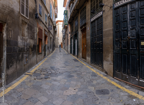 Old shops and old streets in the center of Palma city. Girl walking away
