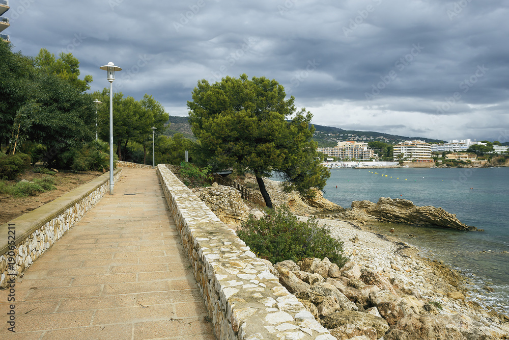 a fragment of a beautiful promenade in the Spanish town of Magaluf on the background of the sea, the city and cloudy sky