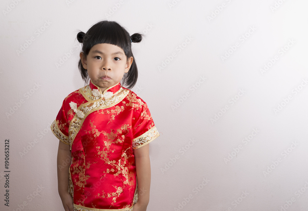 Asian little girl in Chinese dress. Little girl in red dress of Chinese culture. Funny face act of little girl by keeping air in mouth, cheek bulge. Asian little girl in Chinese dress. Little girl in red dress of Chinese culture. Funny face act of little girl by keeping air in mouth, cheek bulge.