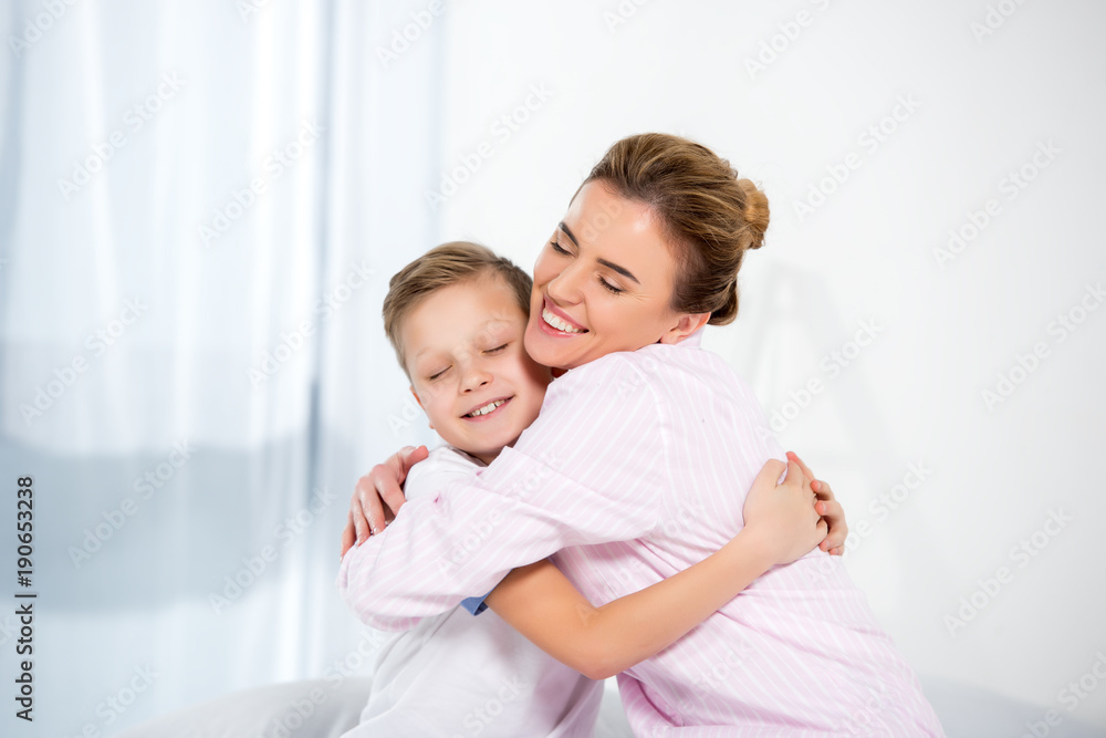 mother and son in pajamas embracing in morning