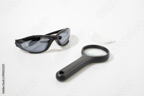 Sun glasses and magnifying glass in a white background