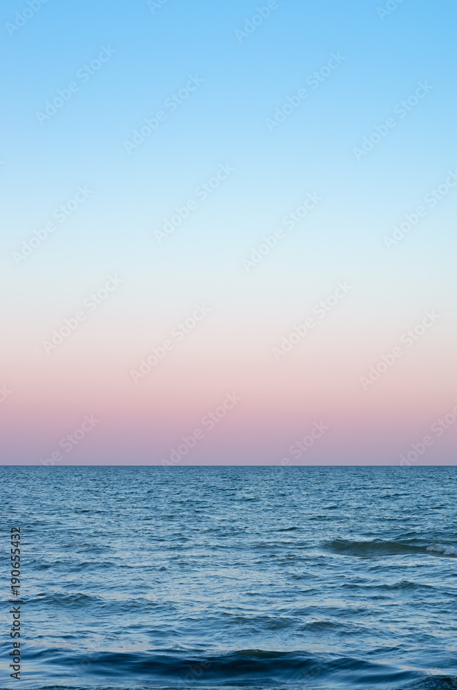 Obraz premium pink sky of sunset on the sea horizon, vertical composition.