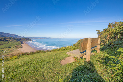 landscape with bench on top of mountain, viewpoint on Vega Neach and Cantabrian Sea, with blue sky, in Ribadesella, Asturias, Spain, Europe
