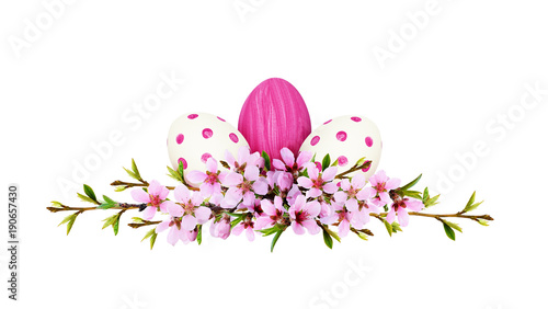 Spring twigs of peach flowers and early leaves with painted eggs in line Easter arrangement
