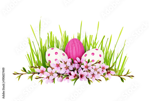 Spring twigs of peach flowers and early leaves with painted eggs and green grass in line Easter arrangement