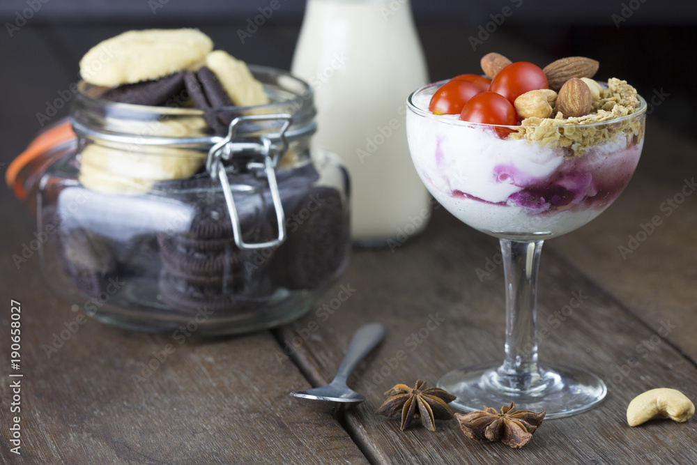 Yogurt with topping tomato almond cashew nut in wine glass with milk on wooden table. Yogurt with topping tomato almond cashew nut in wine glass with milk on wooden table.