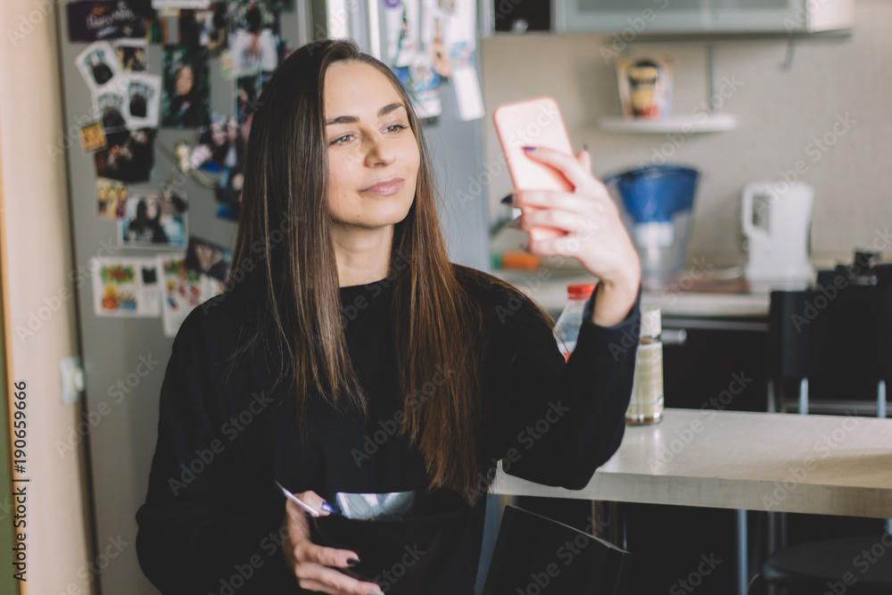 beautiful young brunette girl in a black sweatshirt making selfie and eating cereal beautiful young brunette girl in a black sweatshirt making selfie and eating cereal