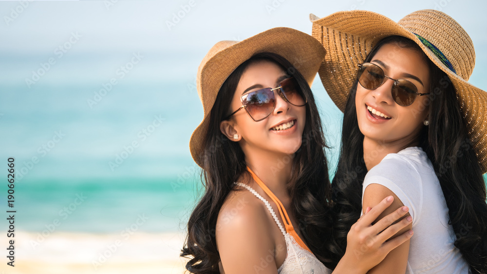 Lesbian couples or close friends are sweet and hug on the beach While relaxing on weekends with blur sea background in travel and holiday concept.