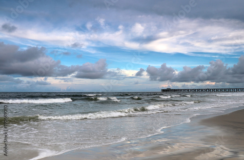 Atlantic ocean beach view. Landscape with cloudy blue sky over atlantic ocean and wooden pier. Atlantic ocean coast at Pawleys Island, Myrtle Beach area, South Carolina, USA.