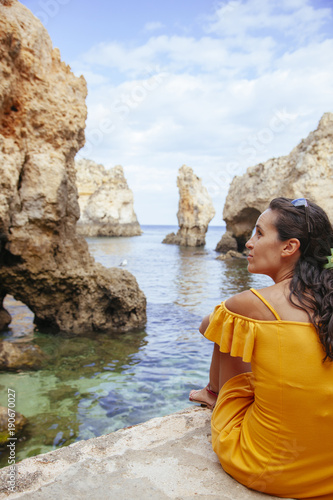 isolated woman on her holidays in the Algarve surrounded by cliffs and sea