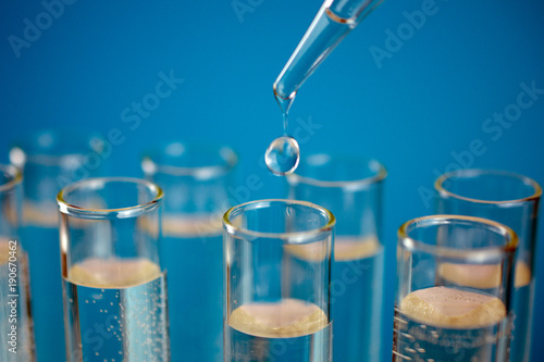 Glass test tubes with laboratory clear liquids, drops from a pipette. Science and laboratory research in the field of medicine. copy space, close up, selective focus , blurred background