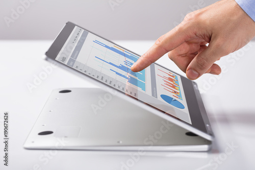 Man Pointing At The Business Graph On Hybrid Laptop