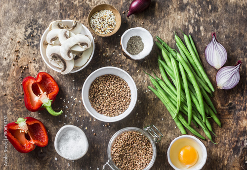 Flat lay healthy vegetarian food ingredients for lunch on a wooden background, top view. Buckwheat, green beans, sweet peppers, red onion, mushrooms, egg - clean eating vegetarian food concept