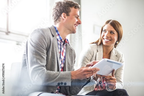 Smiling business people using digital tablet in office