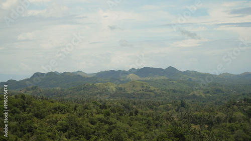 Vew Mountains with rainforest covered with green vegetation and trees on the tropical island, landscape. Mountains and hills with wild forest, sky clouds. Hillside rainforest and jungle. Philippines © Alex Traveler