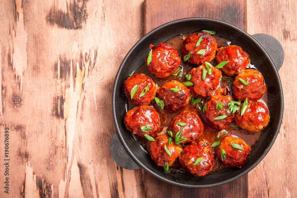 Meatballs in sweet and sour tomato sauce. Homemade roasted beef meatballs in cast-iron skillet