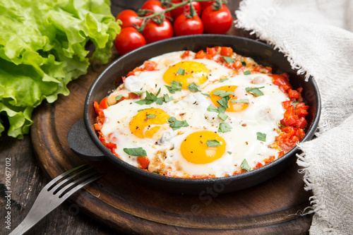 Tasty and Healthy Shakshuka in a Frying Pan. Fried eggs with tomatoes, bell pepper, vegetables and herbs. Middle eastern traditional dish.