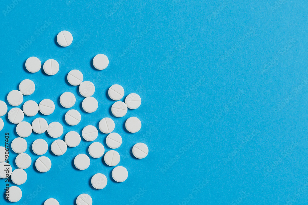 Medication white round tablets arranged abstract isolated on blue color background. Aspirin pills for design. Concept of health, treatment, choice, healthy lifestyle. Copy space for advertisement.