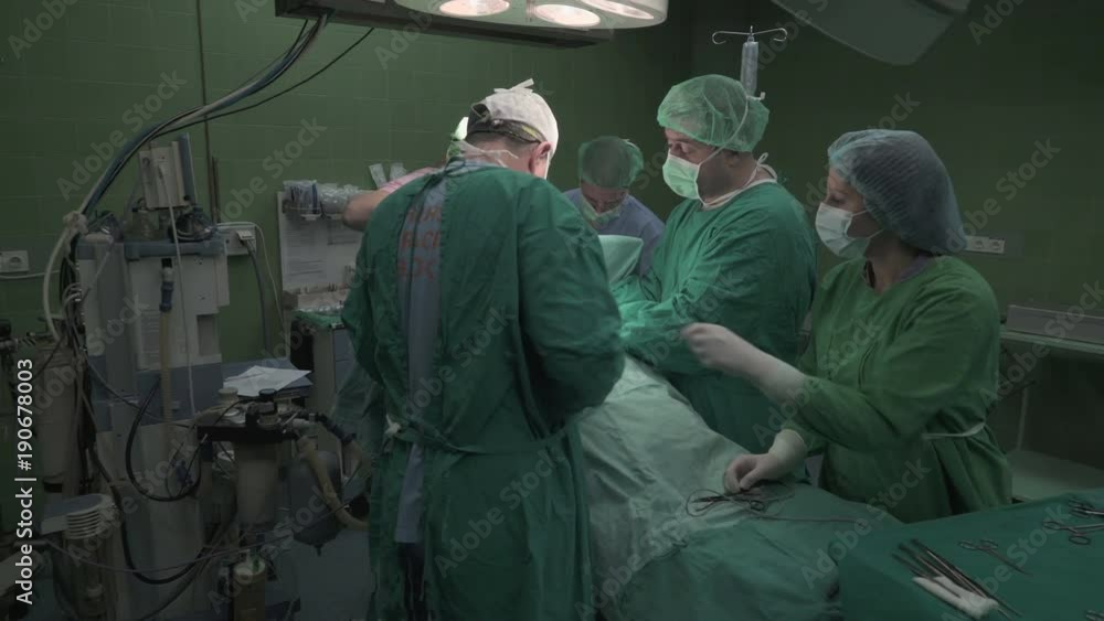 Steady cam shot from portraits of senior surgeons and nurse during surgery operation in operating room, wide angle view,young nurse adding doctor surgical tweezers and the other tools, crane shot