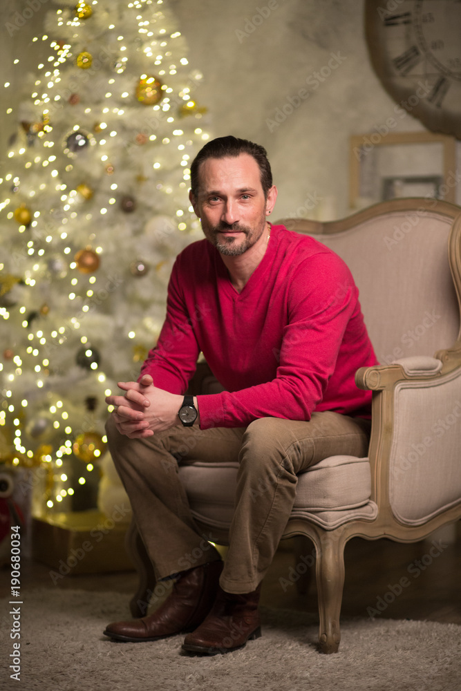 Fototapeta premium Young man with beard sitting in luxury arm chair. looking thoughtful.