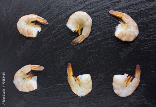 Shrimps on a slate board close-up. Raw tails of tiger shrimps on a slate board, top view.
