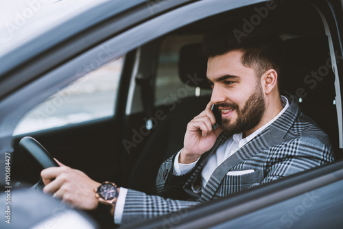 Attractive man wearing a suit making a phone call while driving a car in a city. © dusanpetkovic1