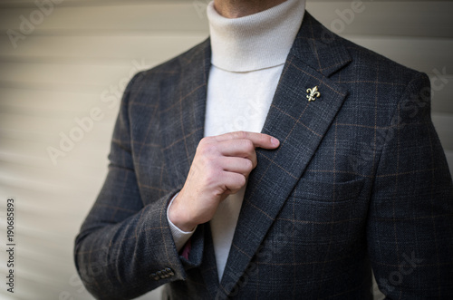 Man in turtleneck sweater suit holding his lapel and posing photo