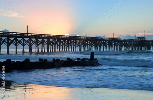 Atlantic ocean beach landscape with amazing colors sky over ocean and wooden pier during morning blue hours before sunrise. USA, South Carolina, Myrtle Beach area, Pawleys Island.