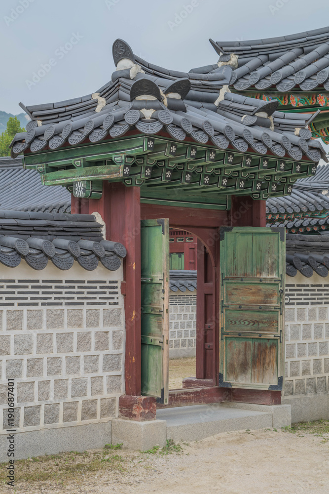 An elaborate entry way, with architectural detail and tile elements, with green doors and a tiled wall, at Gyeongbokgung Palace, Seoul, South Korea An elaborate entry way, with architectural detail and tile elements, with green doors and a tiled wall, at Gyeongbokgung Palace, Seoul, South Korea