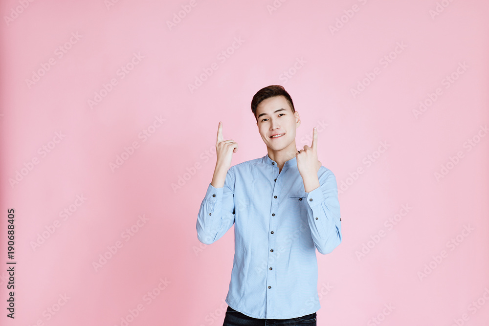 body language and emotions. pink background. Studio shot of attractive man with stylish hair.He pointing upside with both hands and smiles.Copy space. body language and emotions. pink background. Studio shot of attractive man with stylish hair.He pointing upside with both hands and smiles.Copy space.