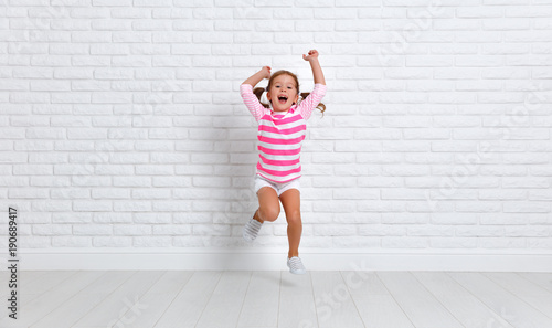 happy child girl jumping around empty wall