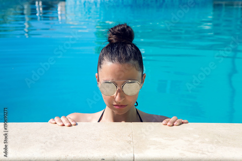 young sexy girl in the pool in sunglasses photo