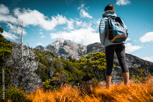 Woman hiker stands on the dry meadow and enjoys mountain views. Patagonia, Argentina