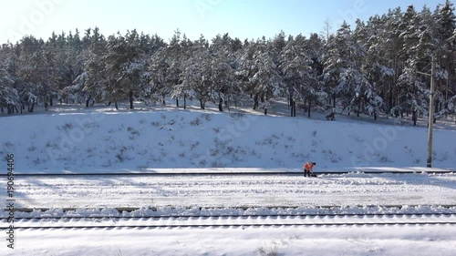 Slow-mo footage. Worker cleans snow on rail station photo