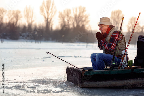 man fishing on the frozen river in winter