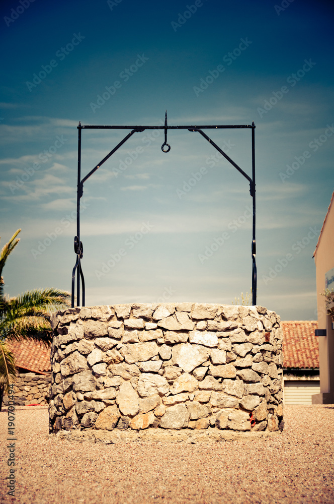 Fototapeta premium well with drinking water in harsh sunlight at noon in south france