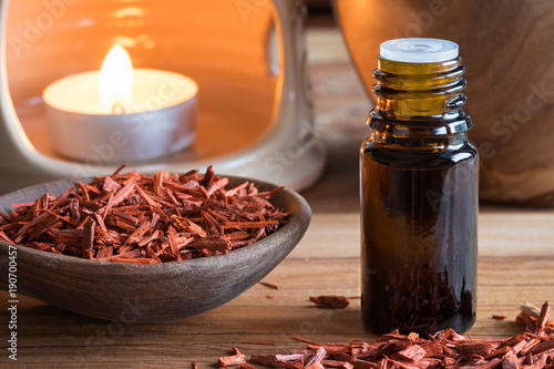 A bottle of sandalwood essential oil with sandalwood pieces photo